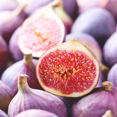 Close-up of LSU purple figs with a halved fig showing pinkish-red interior.